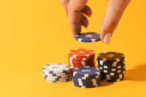 Hand stacking casino chips on yellow background