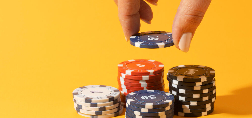 Hand stacking casino chips on yellow background