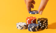 Hand stacking casino chips on yellow background