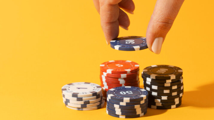 Hand stacking casino chips on yellow background